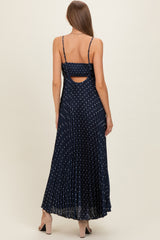 woman wearing a navy blue polka dot maternity maxi dress with a pleated skirt and cutout back detail