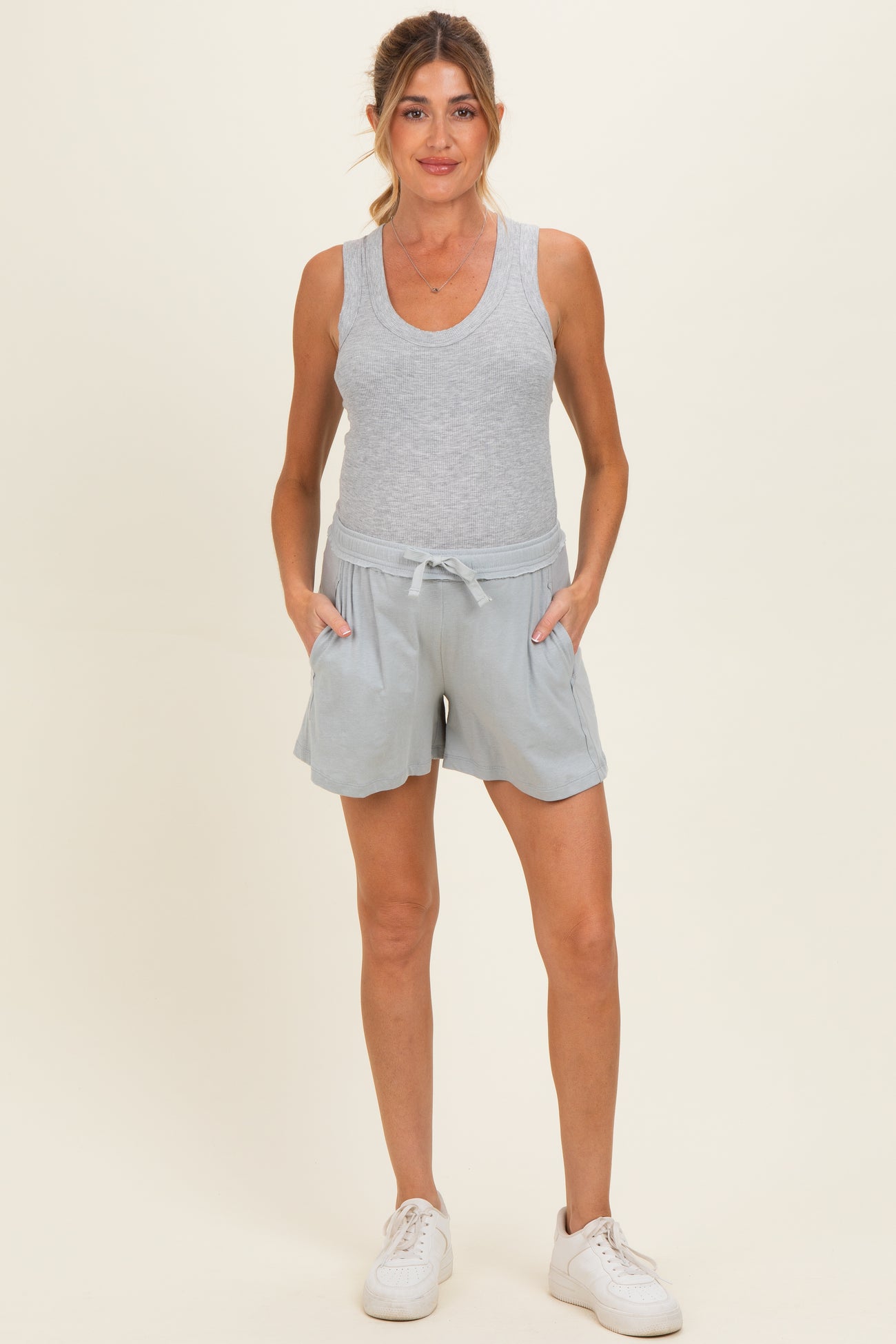 woman wearing a gray maternity tank top and light blue maternity shorts with pockets