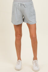 woman wearing light grey maternity shorts with elastic waistband and side pockets, paired with white sneakers