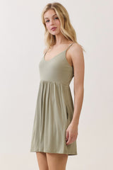 woman wearing a light olive green spaghetti strap dress with a flared skirt