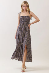 woman wearing a navy blue floral maxi dress with adjustable straps and a side slit