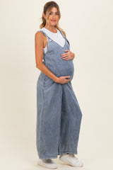 woman wearing a light blue denim maternity overall and holding her baby bump