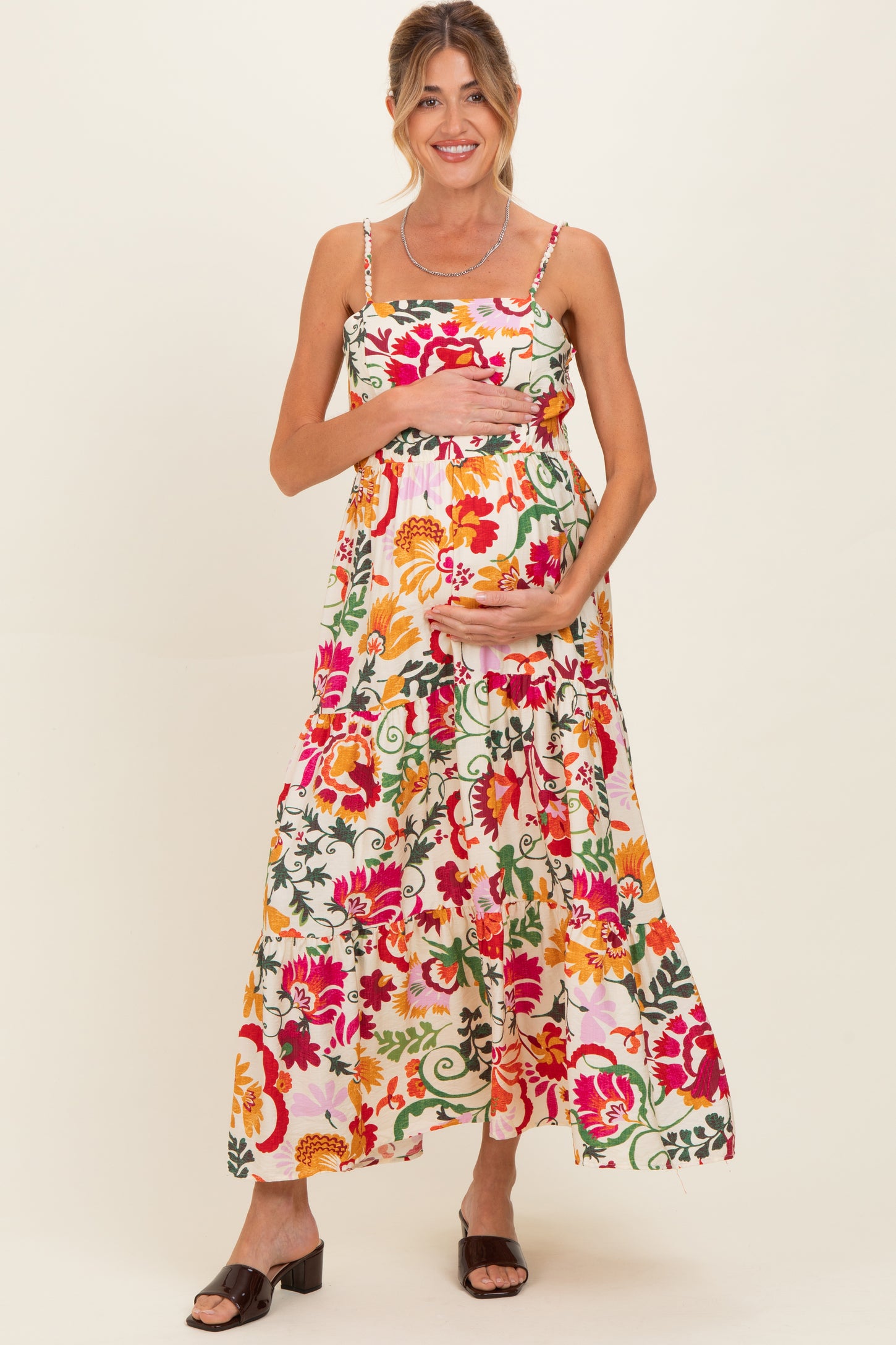 woman wearing a floral maternity maxi dress with a tiered skirt and holding her baby bump