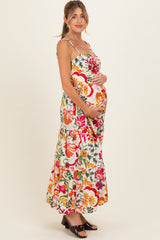 woman wearing a colorful floral maternity maxi dress and holding her baby bump