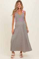 woman wearing a striped maternity maxi dress with a v-neck and pink tie straps, standing and smiling