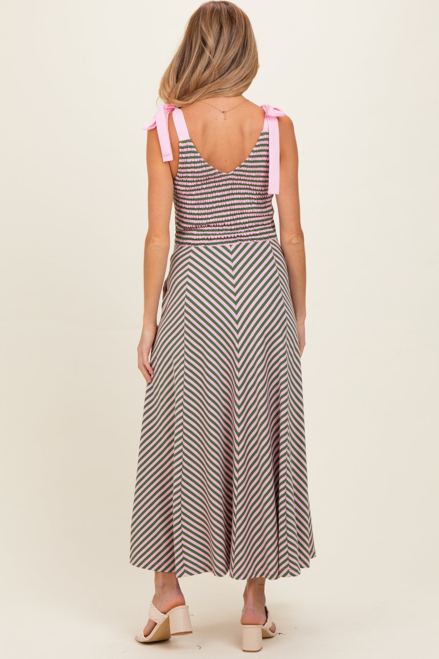 woman wearing a striped maternity dress with a fitted bodice and flared skirt, tied shoulder straps visible from the back