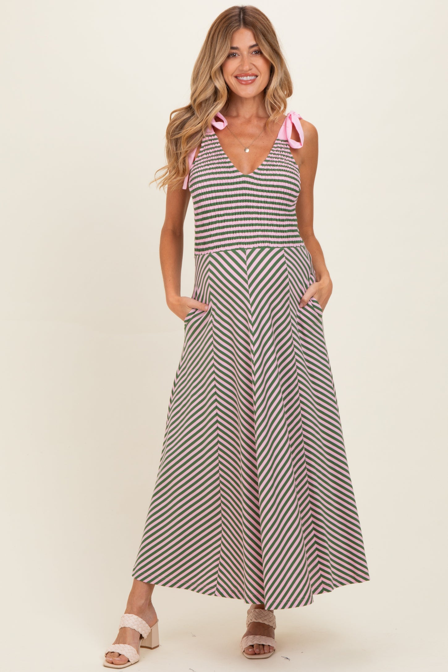woman wearing a striped maternity maxi dress with a v-neckline and tie straps, featuring pockets on the skirt