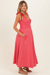 woman wearing a red and white striped maternity dress with a smocked bodice and pockets, showcasing her baby bump