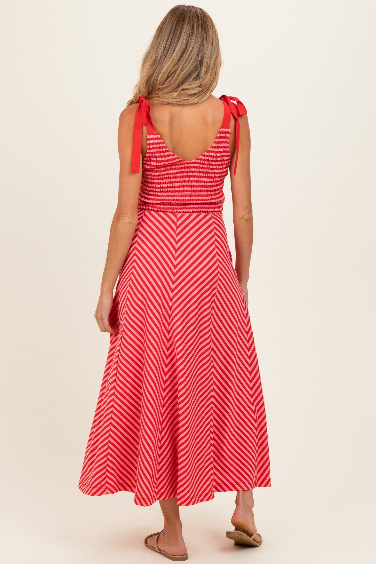 woman wearing a red and white striped maternity dress with a smocked bodice and shoulder ties, showing a relaxed fit