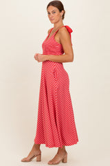 woman wearing a red and white striped maxi dress with a fitted bodice and tie straps, standing sideways