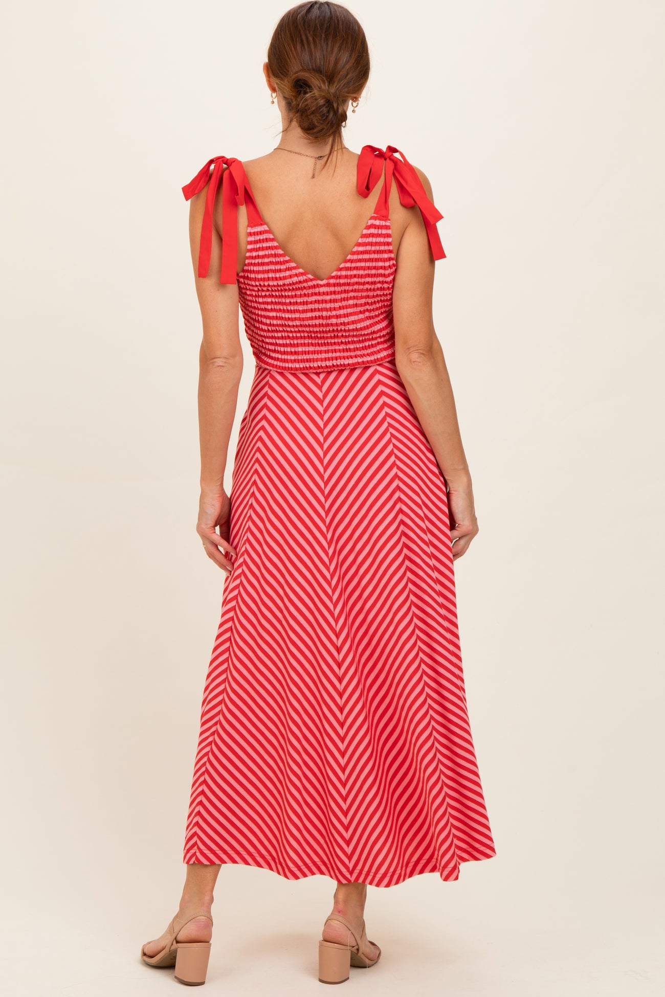woman wearing a red and white striped maxi dress with smocked bodice and tie shoulder straps, shown from the back