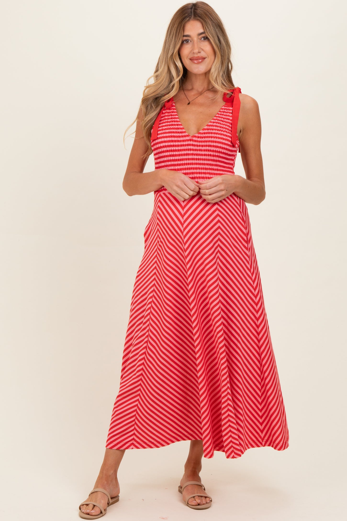 woman wearing a red and white striped maternity dress with a v-neckline and adjustable straps, showing her baby bump