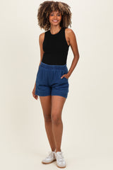 woman wearing a black sleeveless top and blue maternity shorts with an elastic waistband and pockets