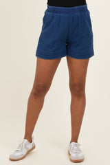 woman wearing navy blue maternity shorts with an elastic waistband and braided detail, styled with white sneakers