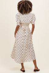 woman wearing a cream maternity dress with brown polka dots and puff sleeves, showing the back view
