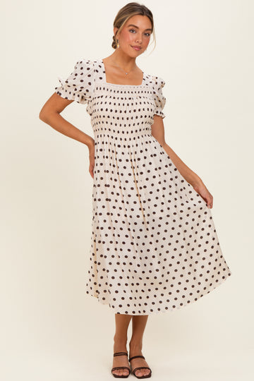 woman wearing a cream polka dot midi dress with puff sleeves and a smocked bodice