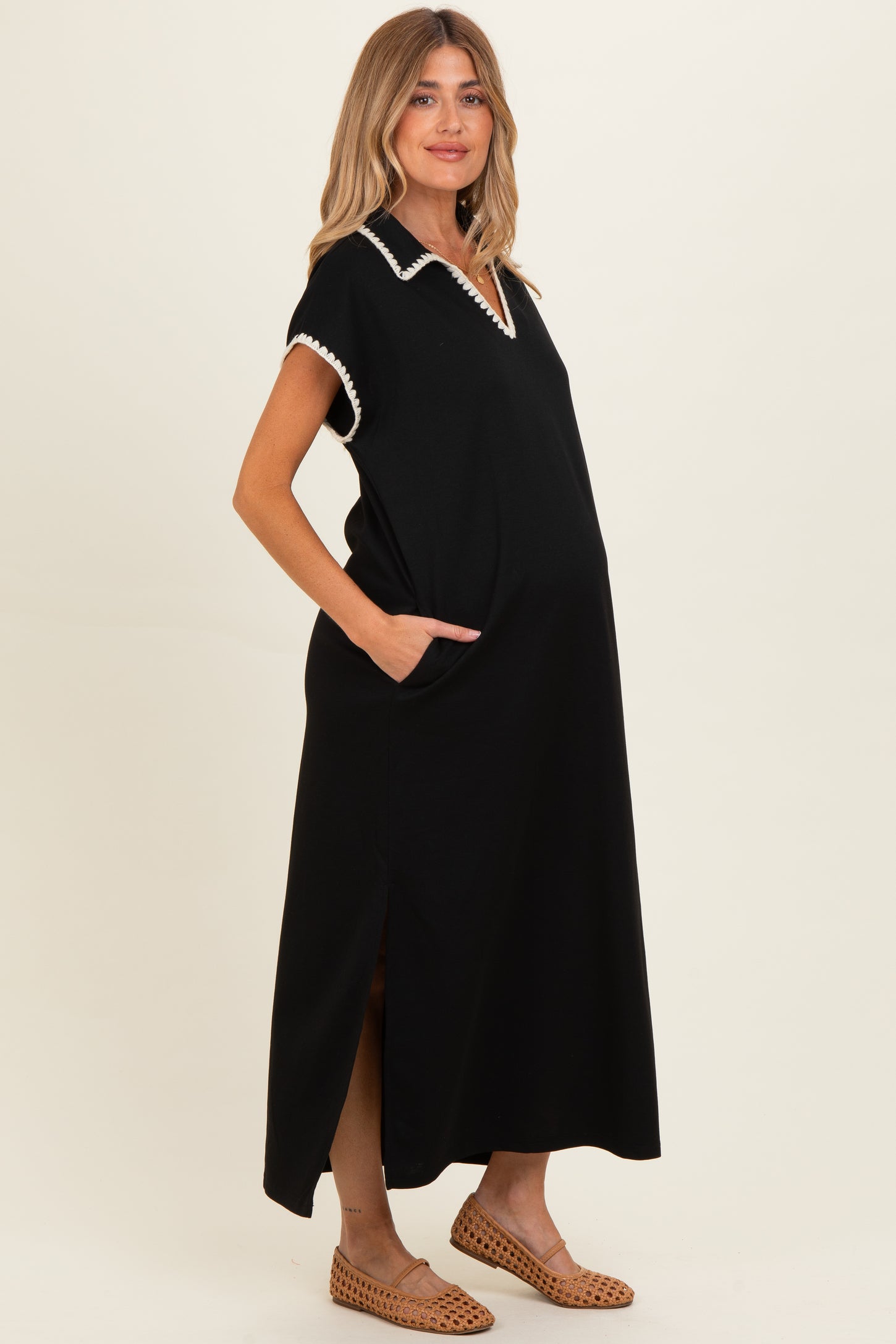 woman wearing a black maternity maxi dress with a collar and pockets, showing her baby bump