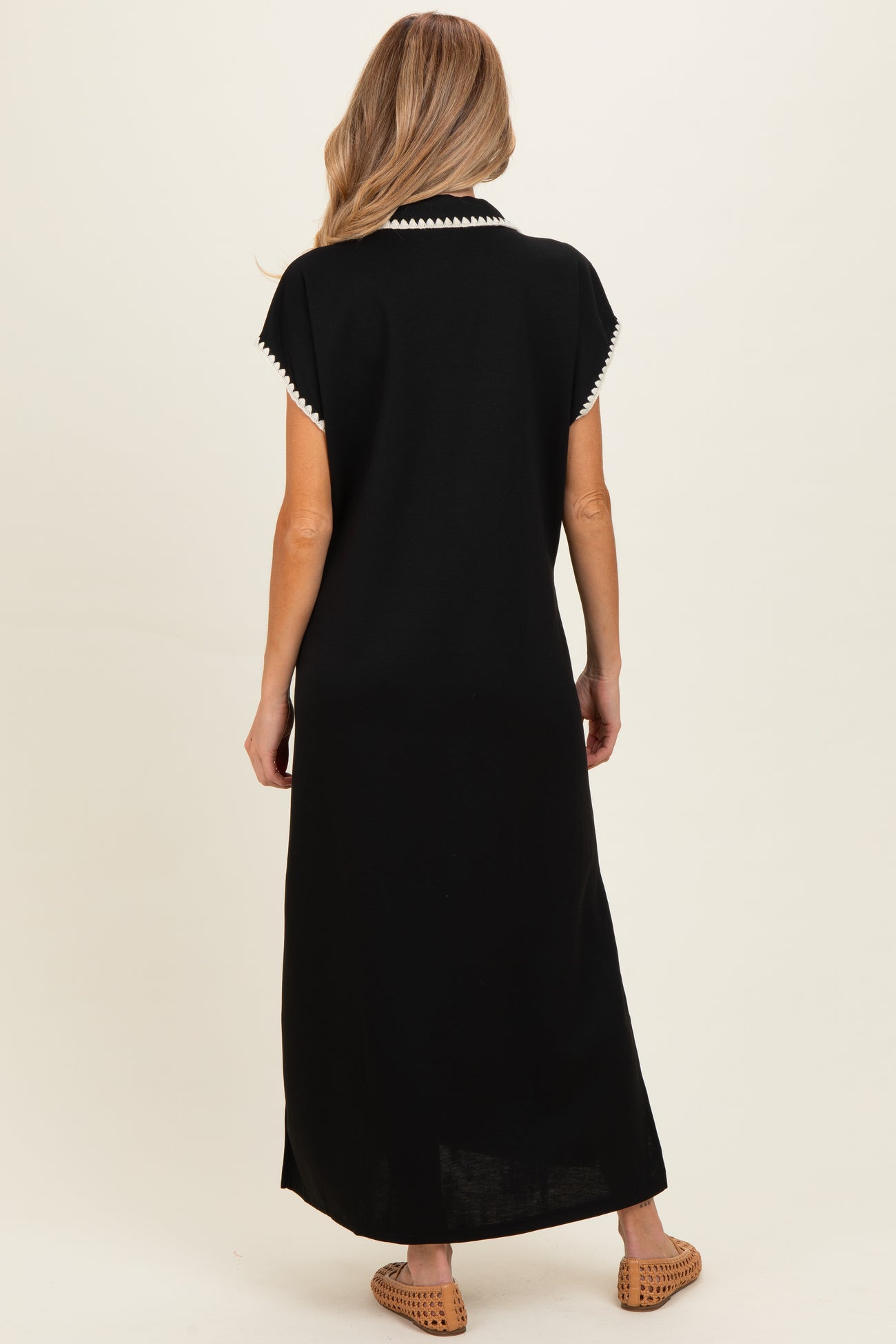 woman wearing a black maternity maxi dress with white trim on the collar, shown from the back