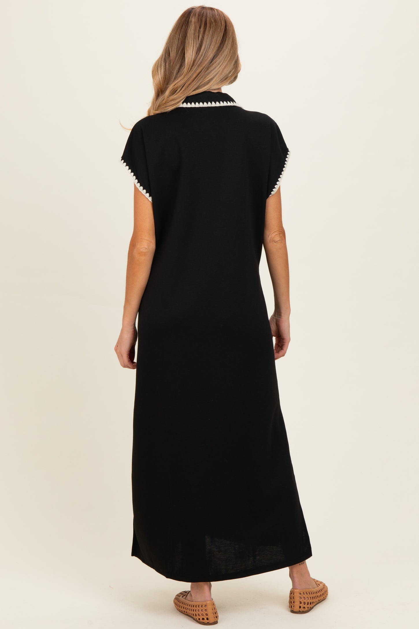 woman wearing a black maternity maxi dress with white trim on the collar, shown from the back