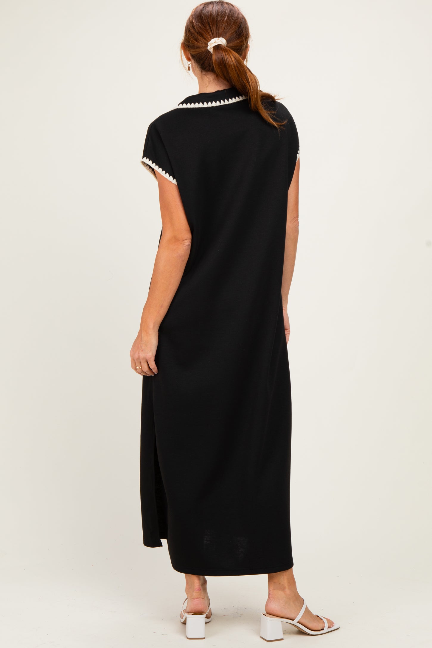 woman wearing a black maxi dress with short sleeves and decorative trim at the neckline, shown from the back