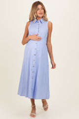 woman wearing a light blue sleeveless maternity dress with button details and holding her baby bump