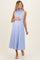 woman wearing a light blue sleeveless maternity dress with button details and holding her baby bump