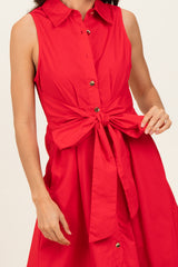 woman wearing a bright red sleeveless dress with a tied waist detail and button front