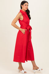 woman wearing a sleeveless red midi dress with a front tie and pockets, styled with white heeled sandals
