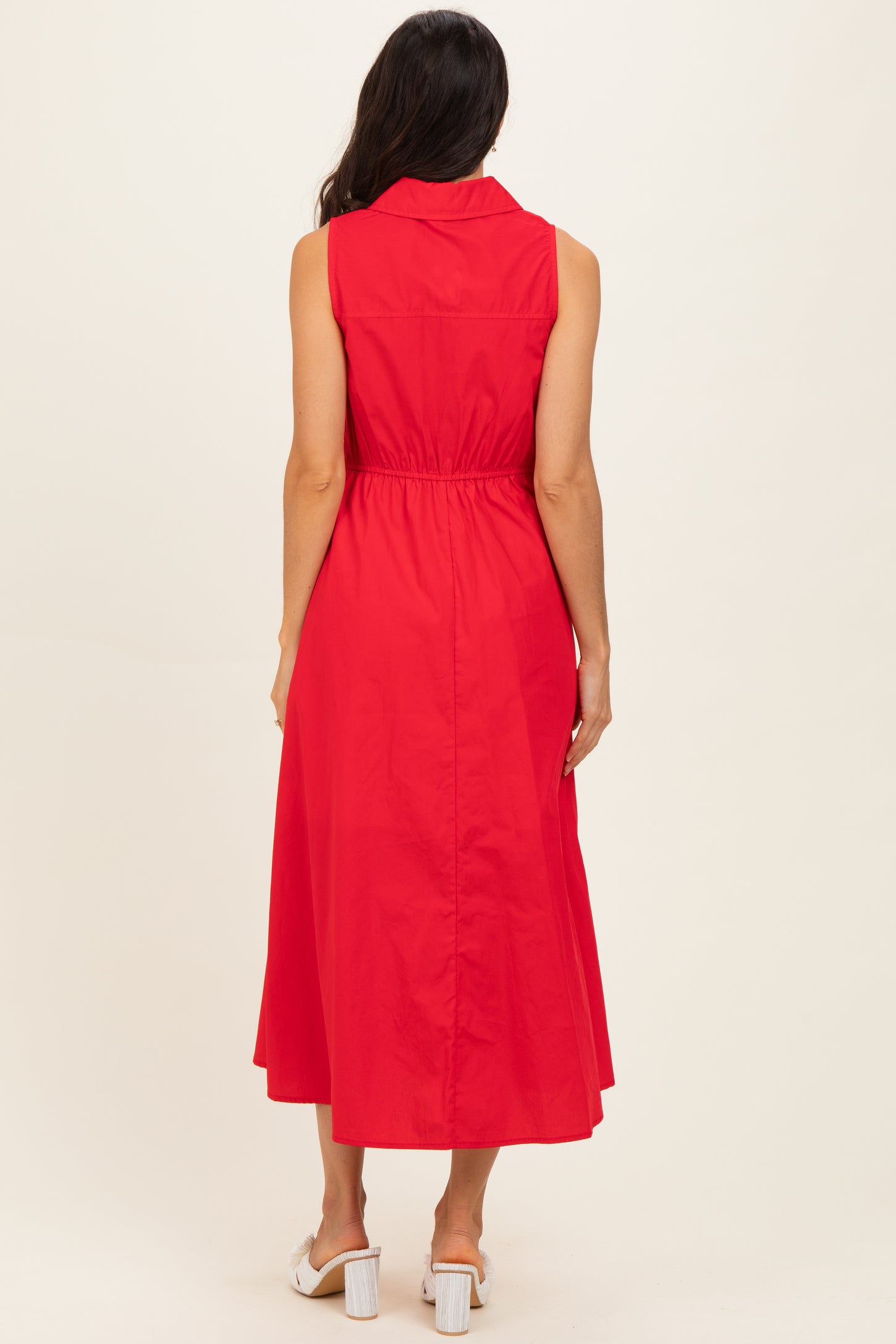 woman wearing a sleeveless red midi dress with a belted waist and a shirt collar, shown from the back