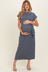 woman wearing a navy and white striped maternity dress with a tie detail and holding her baby bump