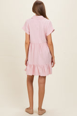 woman wearing a light pink short sleeve maternity dress with a ruffled hem and a button-up collar