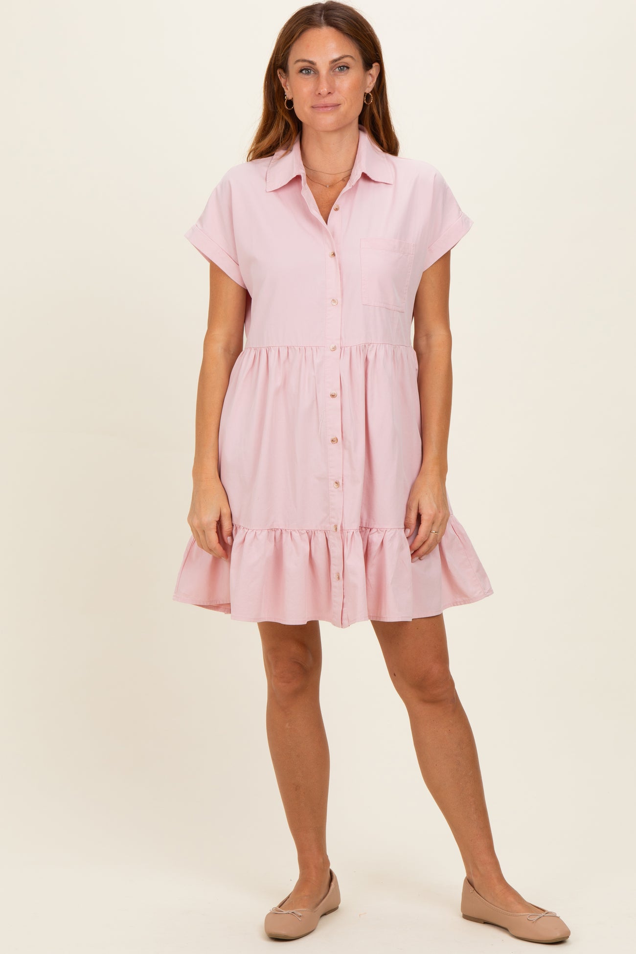 woman wearing a pink short sleeve button-up dress with a tiered ruffle hem and side pockets