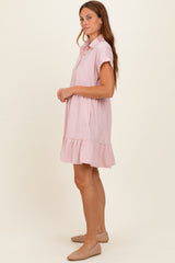 woman wearing a light pink short sleeve shirt dress with a ruffled hem and a pocket on the chest