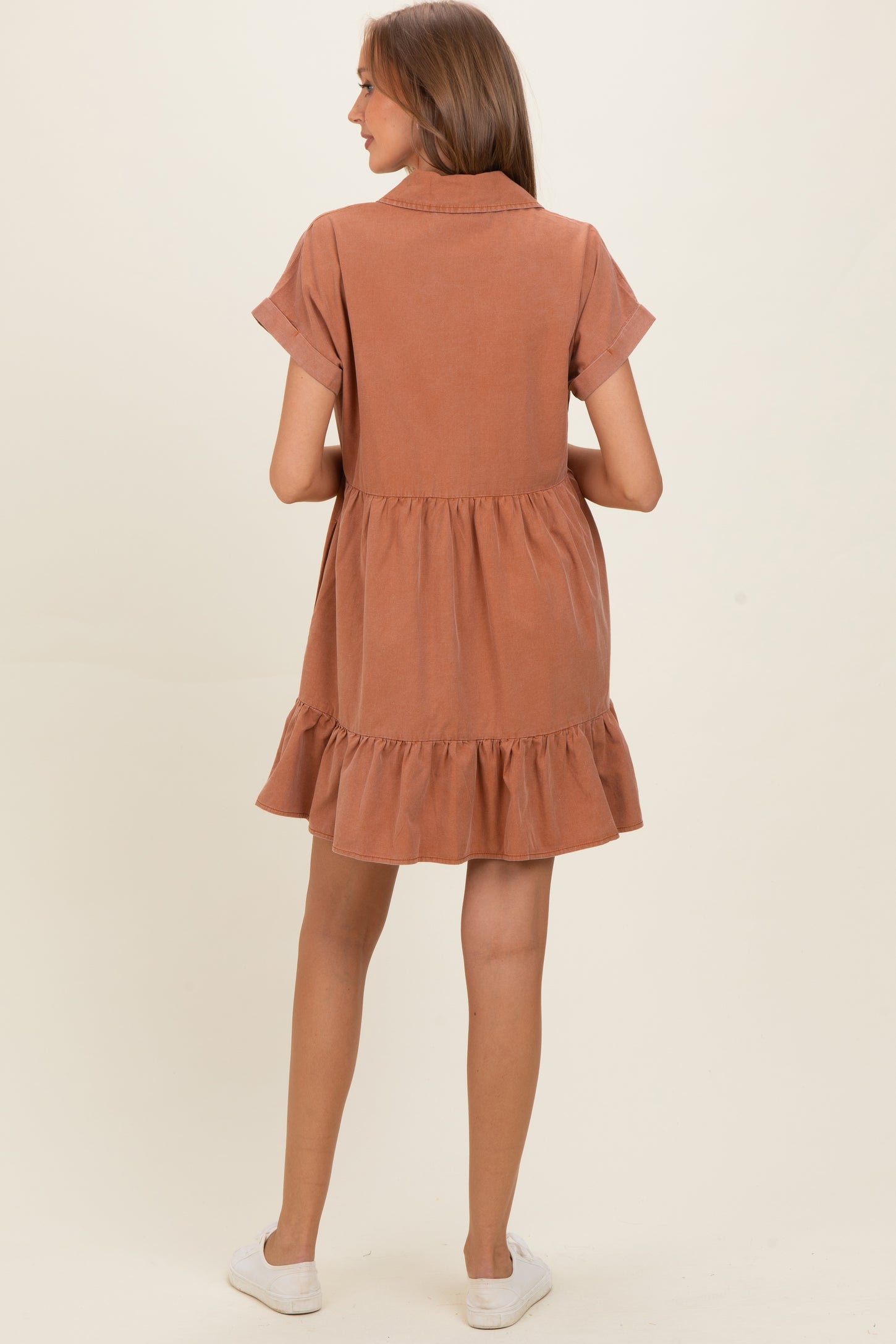 woman wearing a rust-colored short sleeve maternity dress with a tiered ruffle hem