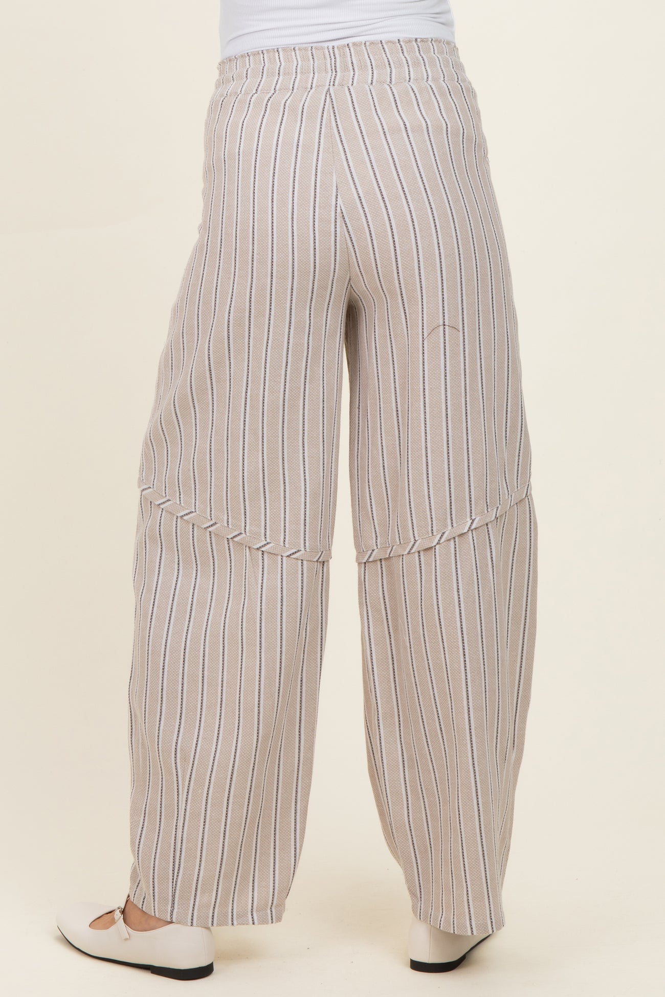 woman wearing light beige striped maternity pants with wide legs, showing the back view