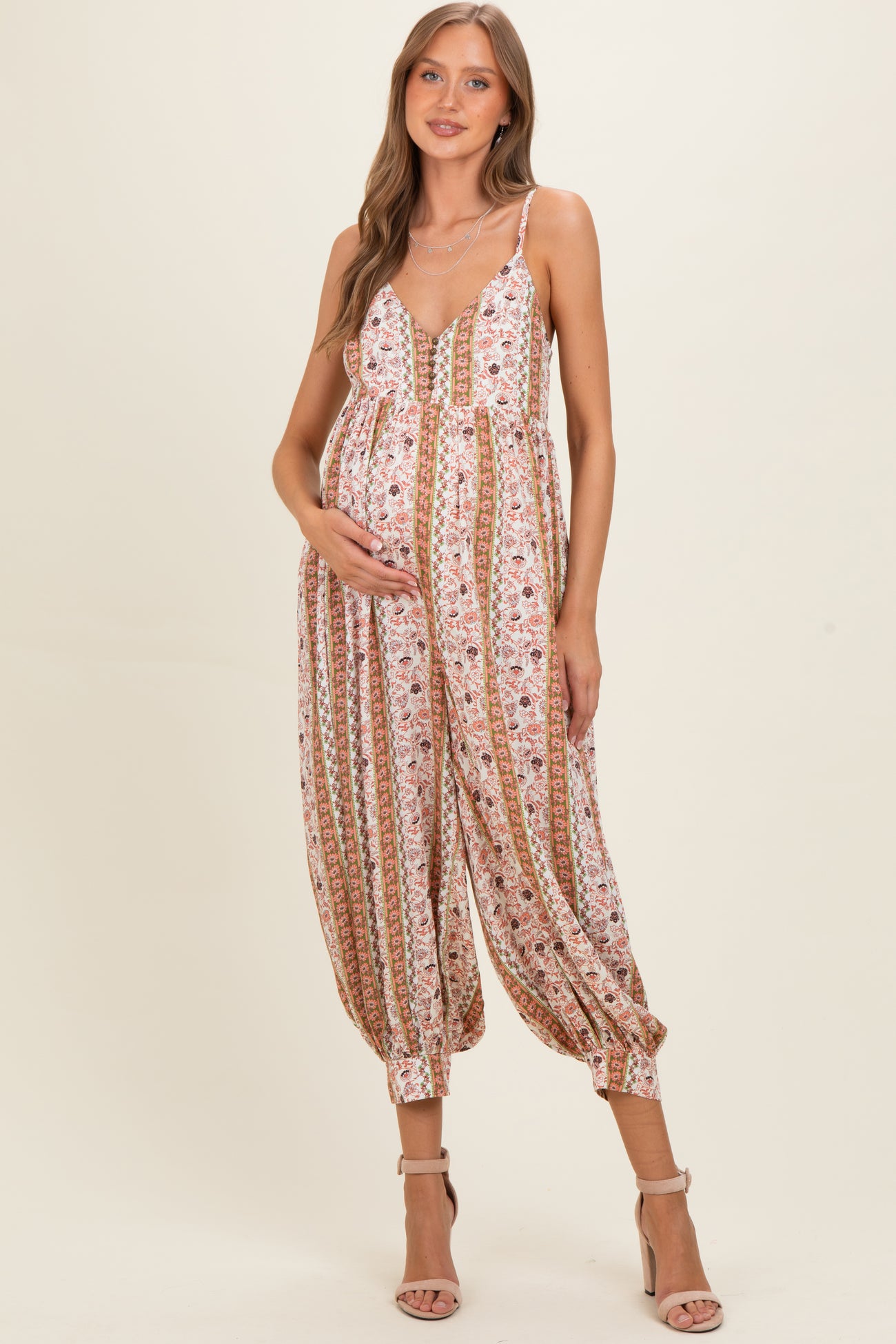 woman wearing a floral patterned maternity jumpsuit and holding her baby bump