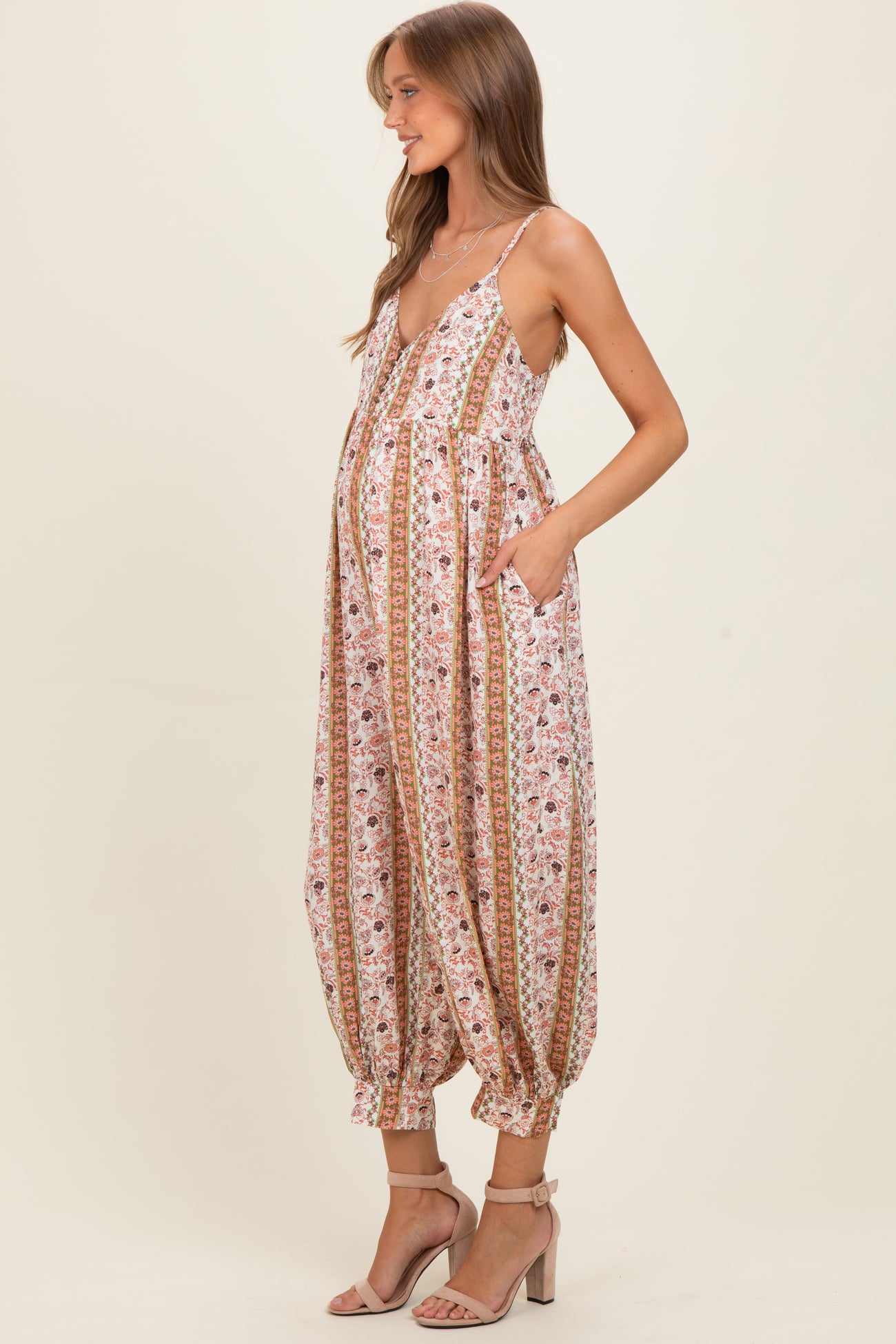 woman wearing a floral maternity jumpsuit with pockets and a visible baby bump