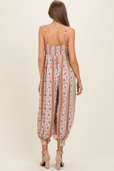 woman wearing a floral print maternity jumpsuit with elastic waistband and tapered legs, showing the back view