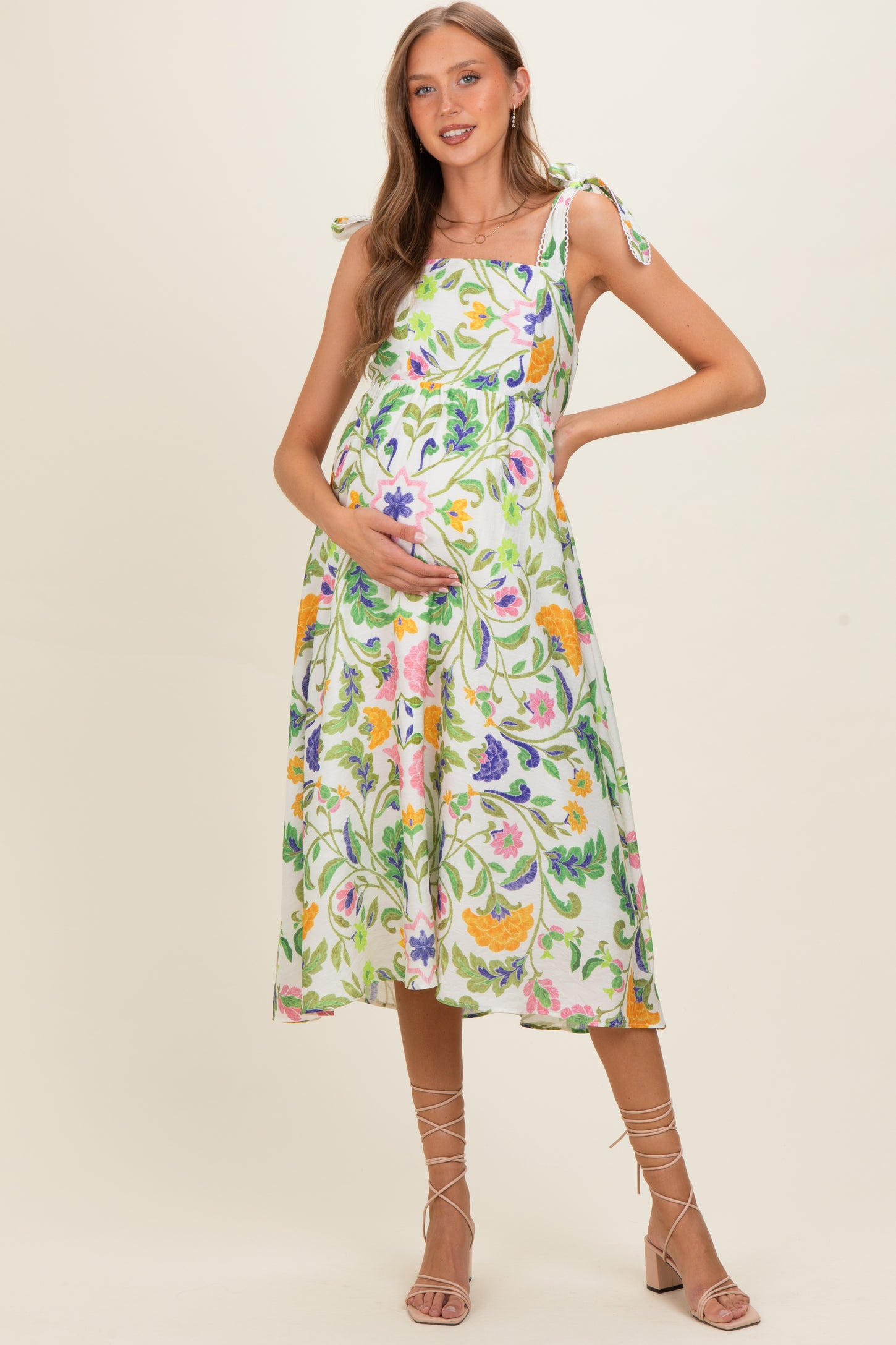 woman wearing a floral maternity dress with tie straps and holding her baby bump