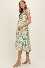 woman wearing a floral print maternity dress with tie straps and holding her baby bump