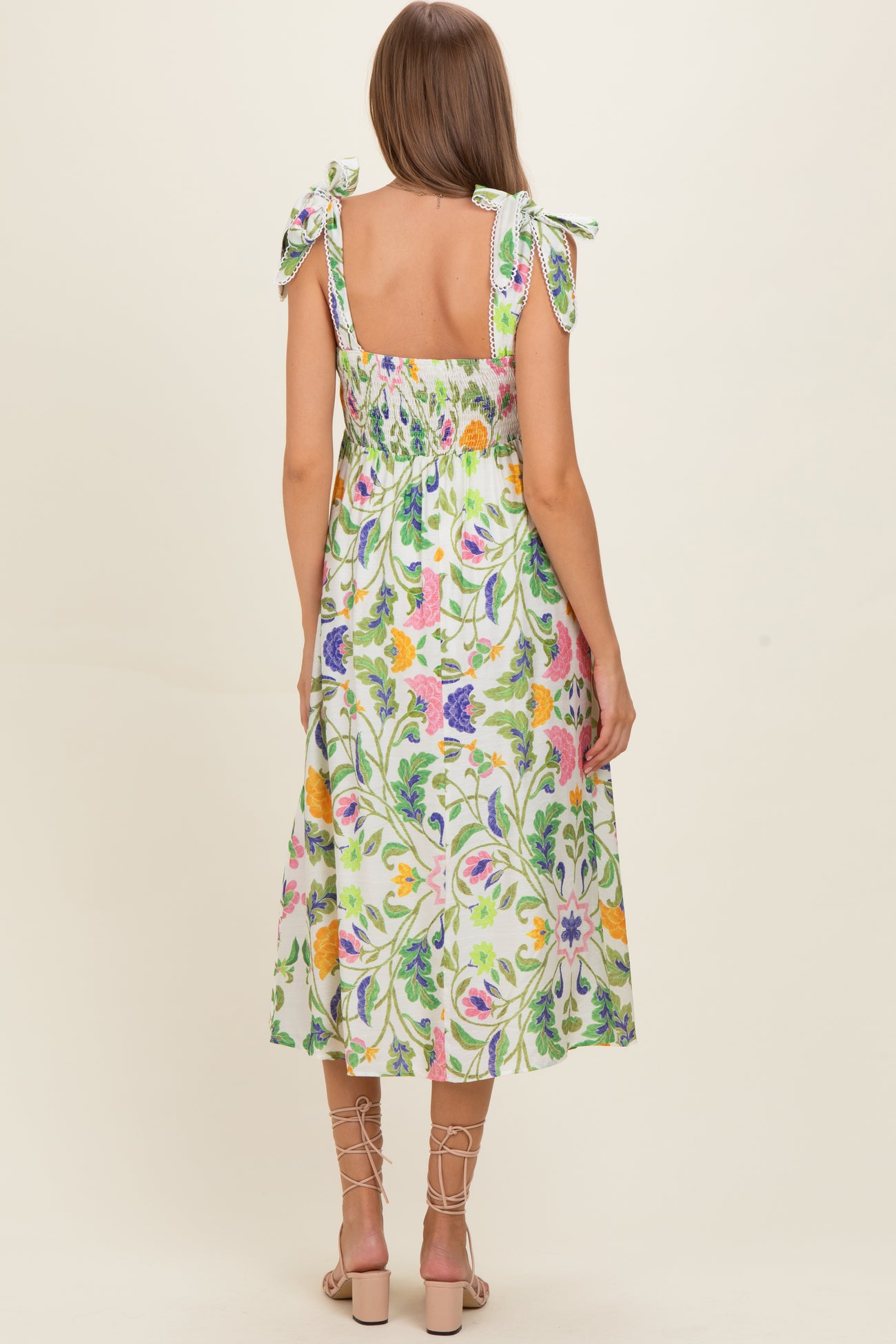woman wearing a floral print maternity dress with tied shoulder straps and a smocked back, revealing a baby bump