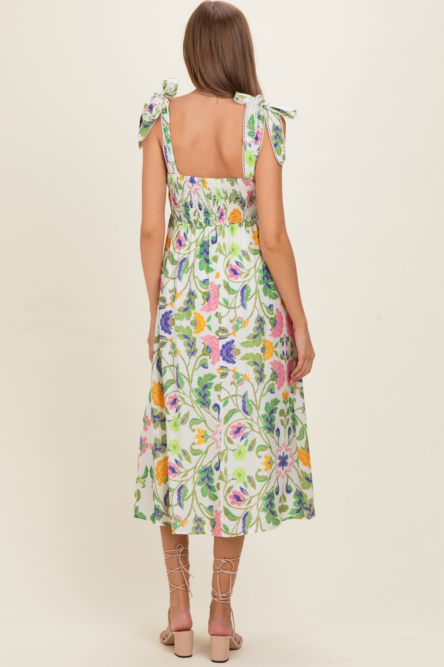 woman wearing a floral print maternity dress with tied shoulder straps and a smocked back, revealing a baby bump
