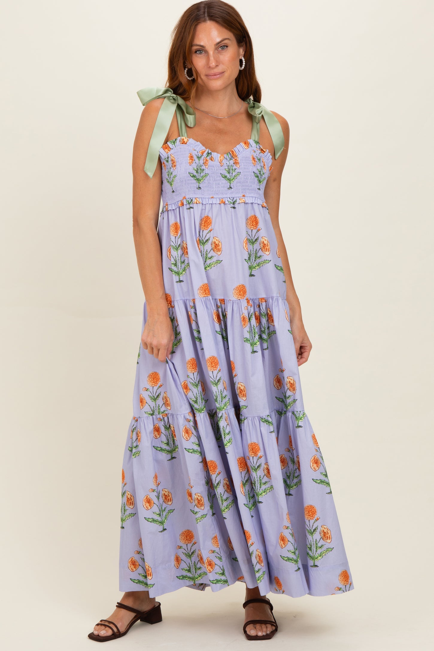 woman wearing a lavender floral maxi dress with smocked bodice and green bow straps