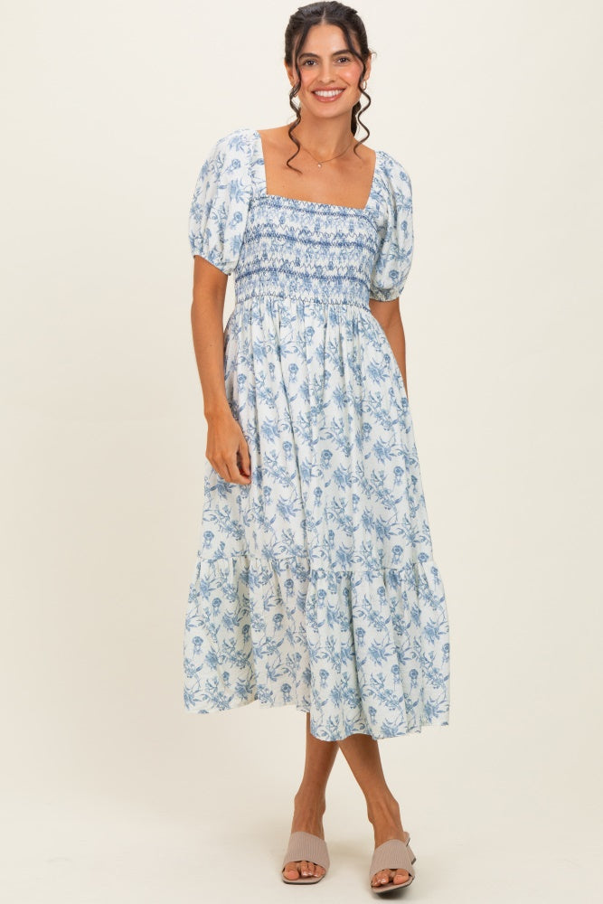 woman wearing a blue and white floral smocked midi dress with puff sleeves and a square neckline