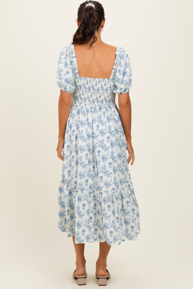 woman wearing a blue floral smocked midi dress with puff sleeves, viewed from the back