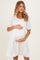 woman wearing a white maternity dress with puff sleeves and holding her baby bump