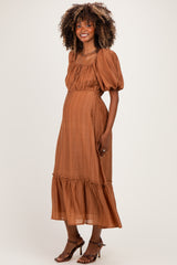 woman wearing a rust-colored maternity dress with puff sleeves and ruffle hem, showing her baby bump