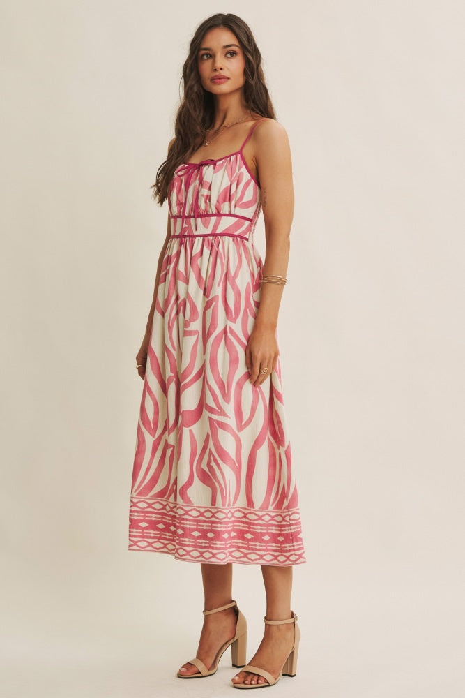 woman wearing a long pink and white printed maxi dress with spaghetti straps and a fitted bodice