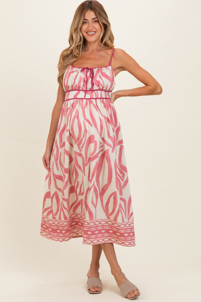 woman wearing a pink and white patterned maternity dress with spaghetti straps and a cinched waist, baby bump visible