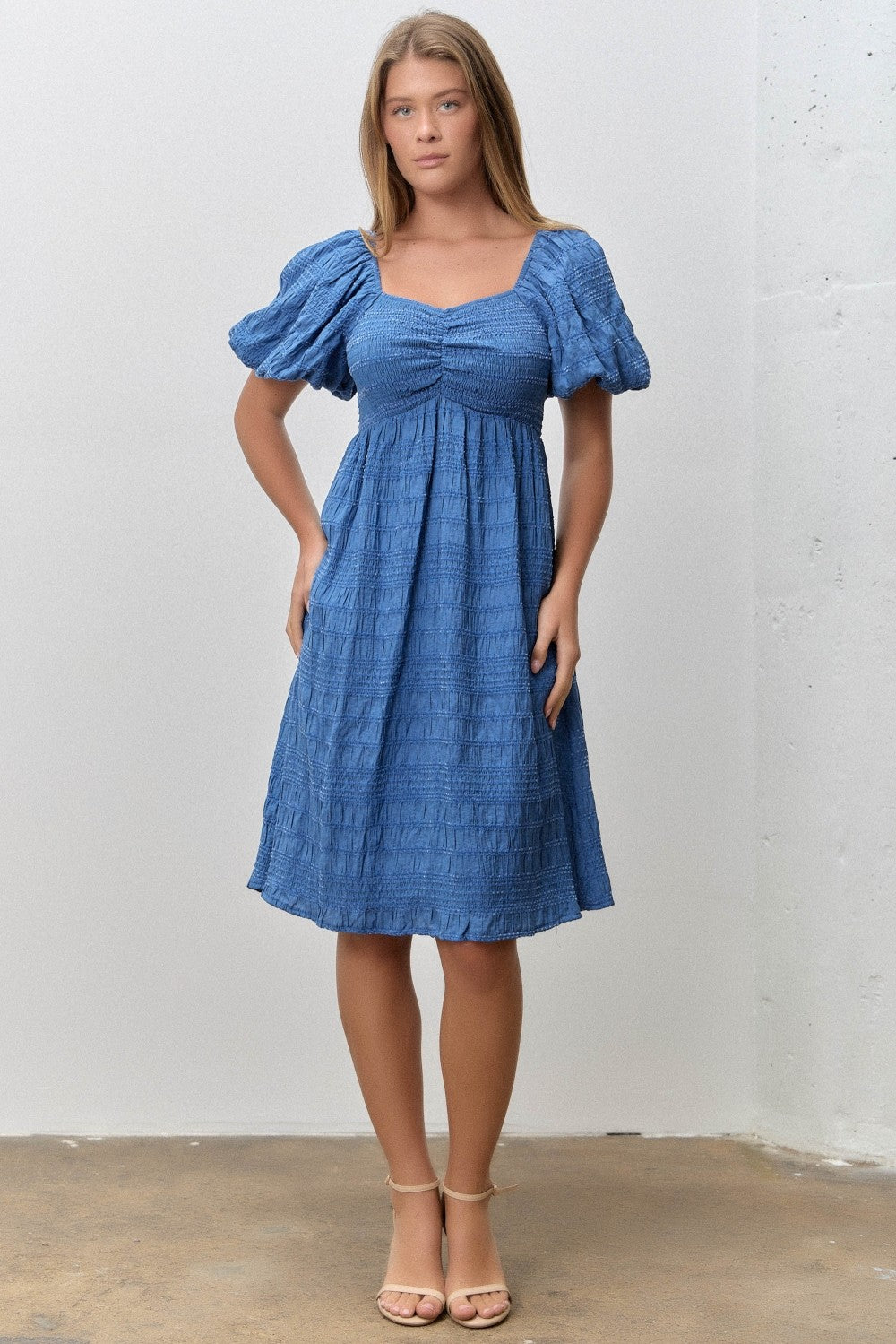 woman wearing a blue smocked dress with puff sleeves and a square neckline